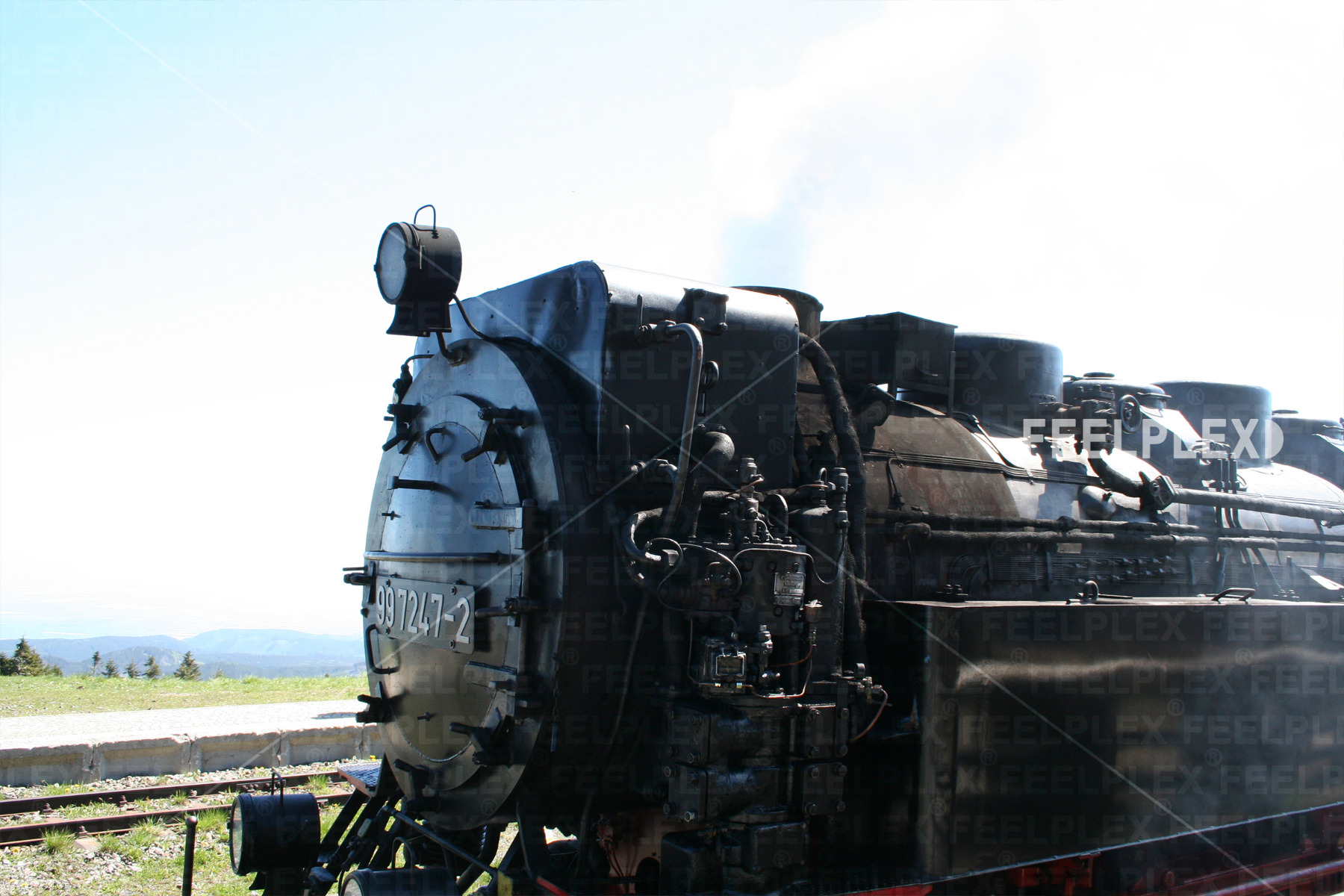 Historic black steam locomotive viewed from the front and side, showing its smokebox and mechanical details
